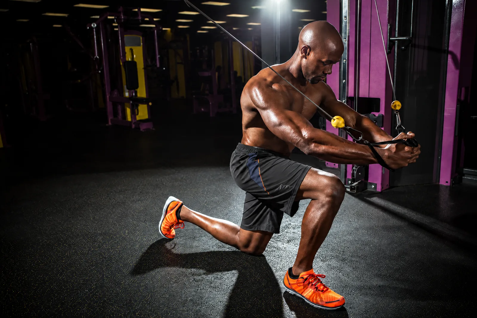 A fit Black athlete performing a cable exercise in black TBE training shorts